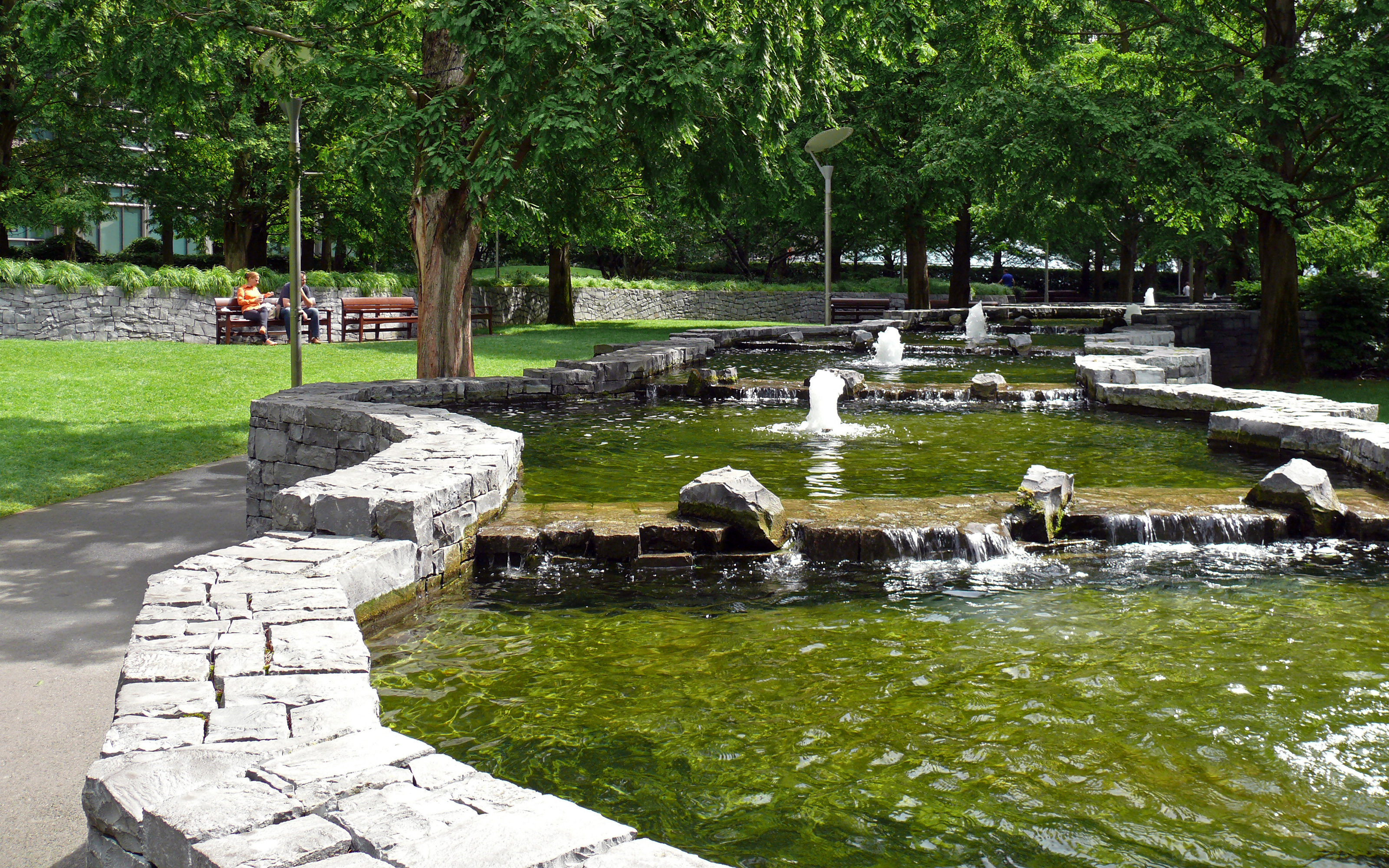 Serpentine stone basins with fountains are the main feature in the park. Channel-like water feature with small fountains